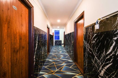 a corridor of a hotel with black marble floors and doors at Collection O Shamshabad Paradise in Shamshabad