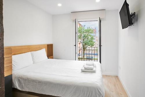 Un dormitorio con una cama blanca y una ventana. en Loft duplex - by Wehomes, en Santander
