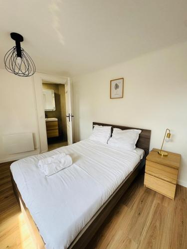 - une chambre avec un grand lit blanc et une table de nuit dans l'établissement Maison design pour 8 pers proche Paris et Disney, à Villiers-sur-Marne