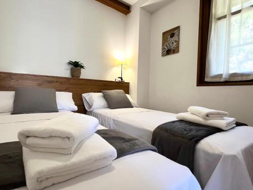 three beds in a room with towels on them at Apartaments Casa Sastressa - L'Amfitriona in Espot