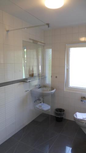 a white bathroom with a sink and a toilet at Pension zur Schmiede in Einruhr