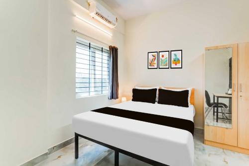 a white bedroom with a bed and a desk at Townhouse Oak Hennur Prakruthi Layout Bangalore in Bengaluru