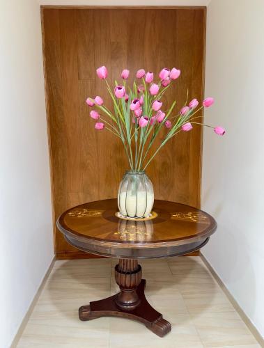 a vase with pink flowers sitting on a table at Hotel Esencia Suites in Lima