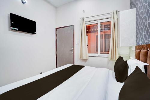a bedroom with a bed with a television and a window at Townhouse Oak Vasundra Nagar in Rajod