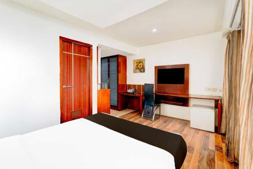 a bedroom with a bed and a desk with a television at Townhouse Oak Pondicherry Opposite to Rock Beach in Puducherry