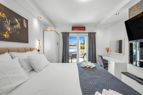 a bedroom with a large white bed and a television at Apartments 1 with pool and private jacuzzi in Vodice