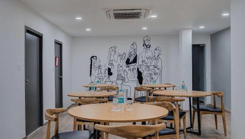 a room with tables and chairs with a drawing on the wall at Townhouse Oak T Nagar Chennai in Chennai
