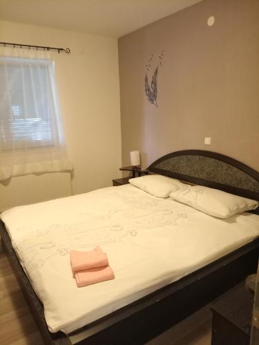 a bedroom with a large white bed with two towels on it at Apartmani Tomljenović in Senj