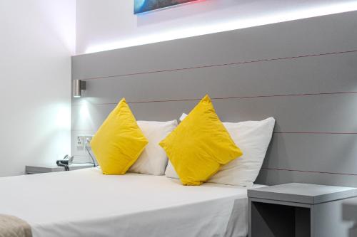 a bedroom with yellow pillows and a white bed at Ilford Hotel Goodmayes in Ilford