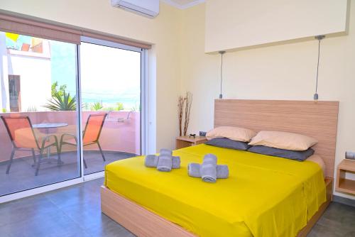 a bedroom with a yellow bed and a balcony at Callista sea view or garden in Kissamos