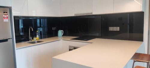 a white kitchen with black walls and white cabinets at Star Residence KLCC By Cozy in Kuala Lumpur