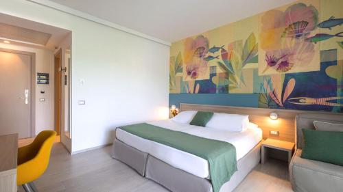 a hotel room with a bed and a chair at Hotel President in Lignano Sabbiadoro