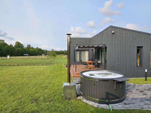 a small house with a hot tub in a yard at Budas in Plieņciems