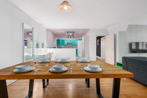 une table en bois avec des assiettes et des verres au-dessus dans l'établissement Iconic Canal Street Apt by City SuperHost, à Manchester