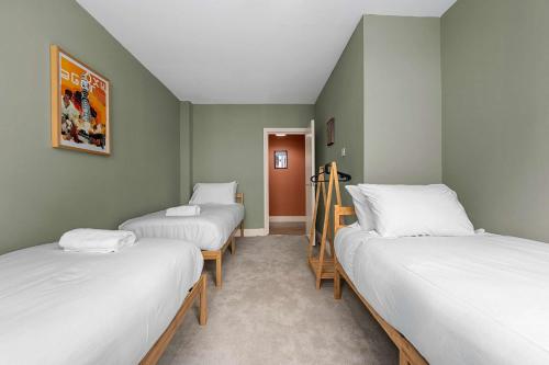 three beds in a room with green walls at Iconic Canal Street Apt by City SuperHost in Manchester