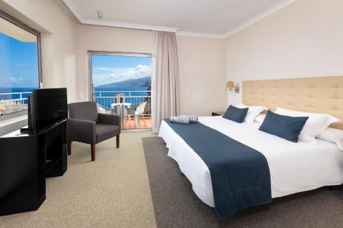 a hotel room with a bed and a television and a balcony at Hotel Atlantic El Tope in Puerto de la Cruz