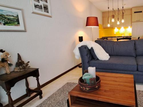 a living room with a blue couch and a table at Waldhaus - CharmingStay in Flumserberg