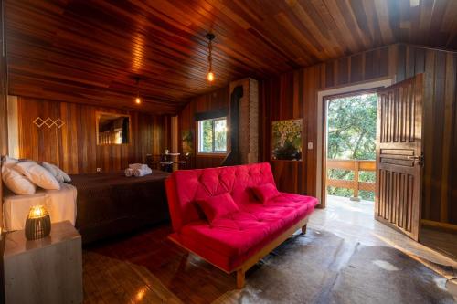 a red couch in a room with a bed and a window at Recanto Lira 1 e 3 in Monte Verde