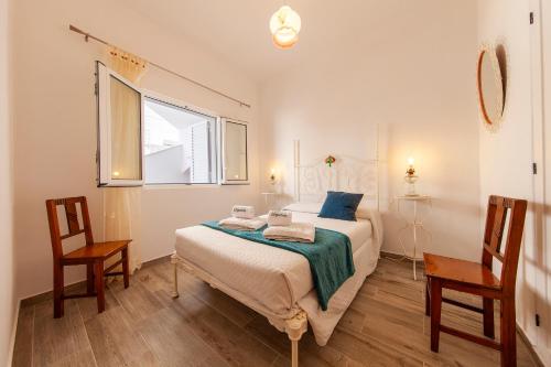 a bedroom with a bed with two chairs and a window at Abrotea Apartments in Lagos