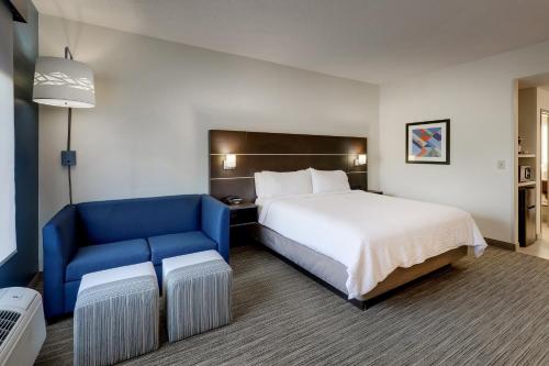 a hotel room with a bed and a blue chair at Holiday Inn Express Hotel & Suites- Gadsden by IHG in Gadsden
