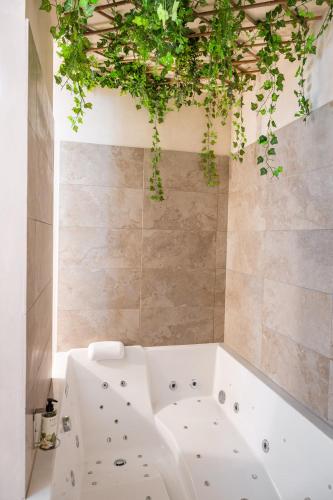 une baignoire blanche avec des plantes suspendues au plafond dans l'établissement Le Jardin Secret - Suite Bali avec Balnéo, à Carpentras