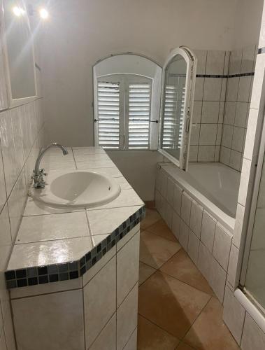 une salle de bain avec un lavabo, une baignoire et un miroir dans l'établissement Appartement 5 personnes village provençal du haut var claviers, à Claviers