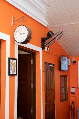 a clock on the wall of a room with orange walls at Resort Palmeiras Dourado in Cansaulim