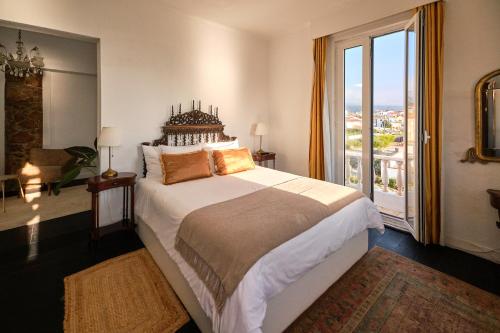 a bedroom with a large bed and a large window at Casal Santa Virginia in Sintra