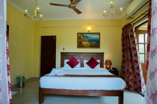 a bedroom with a large white bed with red pillows at Resort Palmeiras Dourado in Cansaulim