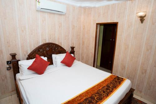 a bedroom with a white bed with red pillows at Resort Palmeiras Dourado in Cansaulim