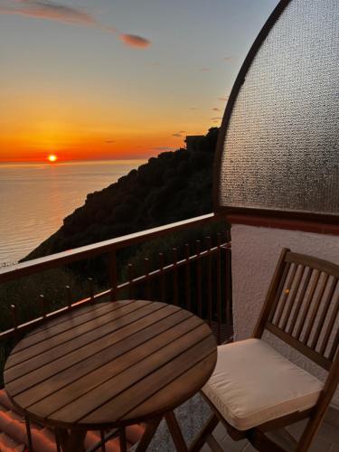 a table and a chair on a balcony with a sunset at Belvedere in Pisciotta