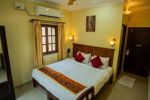 a bedroom with a large white bed with red pillows at Resort Palmeiras Dourado in Cansaulim