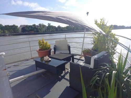 a patio with chairs and a table and an umbrella on a boat at Péniche UHARTEA chambre d'hôtes "Baionako Gambara" in Bayonne