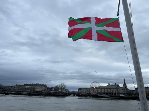 un drapeau flottant sur une rivière à côté d'une ville dans l'établissement Péniche UHARTEA chambre d'hôtes 