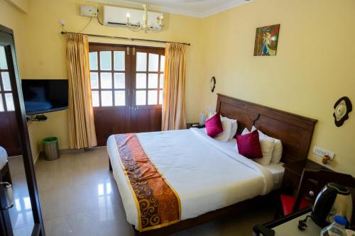 a bedroom with a large bed with pink pillows at Resort Palmeiras Dourado in Cansaulim