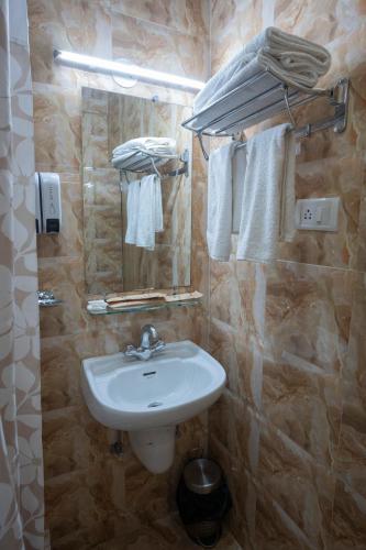 a bathroom with a sink and a mirror and towels at Resort Palmeiras Dourado in Cansaulim