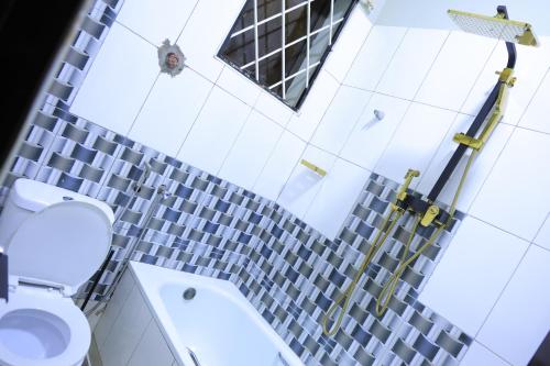 a bathroom with a toilet and a tile wall at AG Home - One Bedroomed Kampala in Kampala