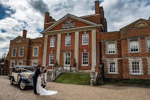 a bride and groom standing in front of a mansion at Warbrook House Heritage Hotel in Hook