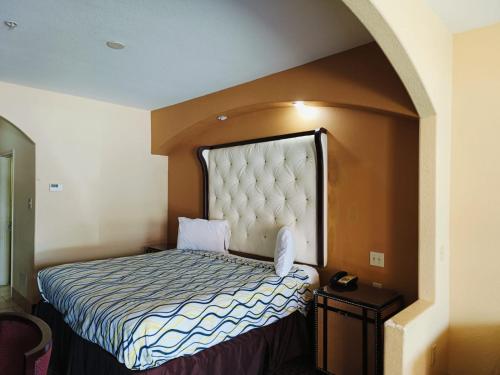 a bedroom with a bed with a large headboard at Capital O Deluxe Inn Channelview Houston I-10 in Channelview