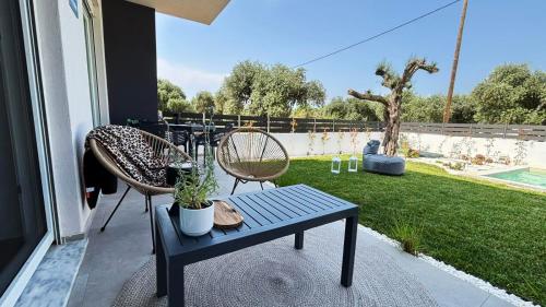 a patio with a bench and two chairs and a yard at Vagia's House in Skala Rachoniou
