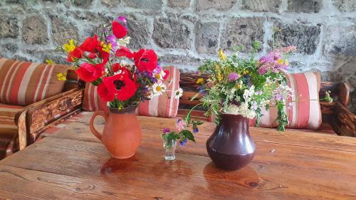 two vases filled with flowers on a wooden table at Geologist's House in Garrgarr