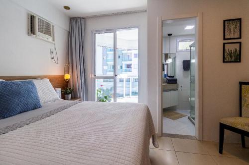 a bedroom with a bed and a glass door to a bathroom at 2Q Casal • Suíte c/ AC • Vista • 2º Andar • NOMDS in Itaparica