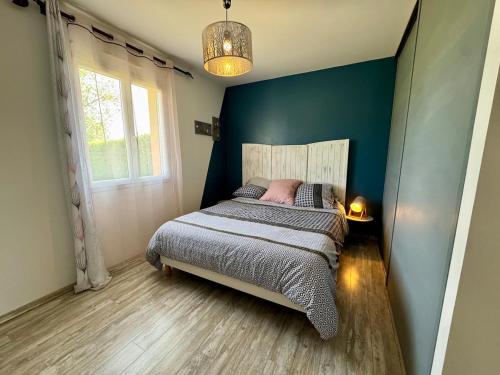 une chambre avec un lit et un mur bleu dans l'établissement L'Évasion Vendéenne - Spacieuse Maison, à Aubigny