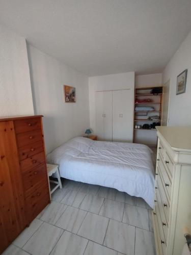 une chambre avec un lit et une commode en bois dans l'établissement Appartement à 2KM de la plage, à Fréjus