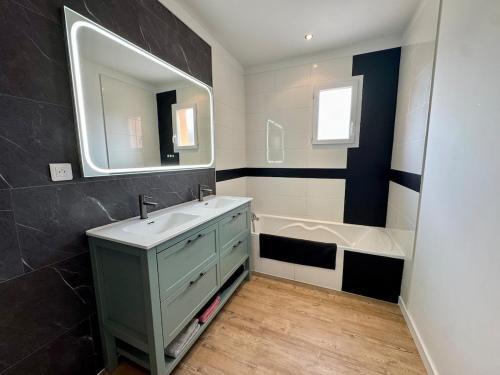 une salle de bain avec un lavabo, un miroir et une baignoire dans l'établissement L'Évasion Vendéenne - Spacieuse Maison, à Aubigny