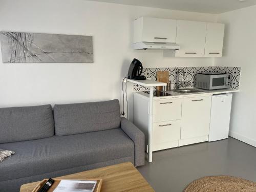 un salon avec un canapé et une cuisine dans l'établissement Appartement proche mer, à Aytré