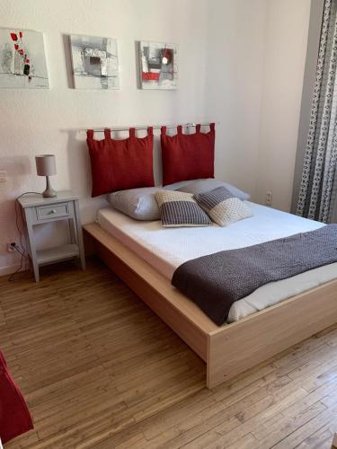 une chambre avec un grand lit avec des oreillers rouges dans l'établissement Gîte Villa la Garenne Ctre ville St Jean de Monts, à Saint-Jean-de-Monts