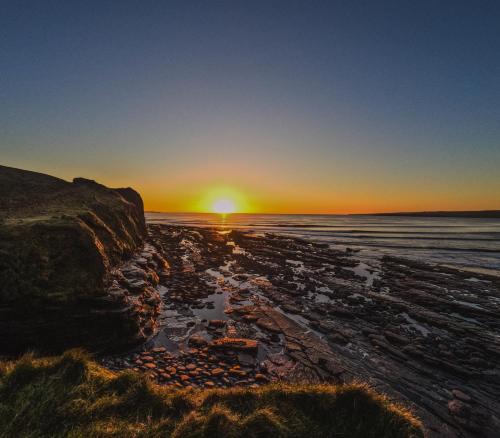 a sunset over the ocean with a rocky beach at Coach House Lodge in Lahinch