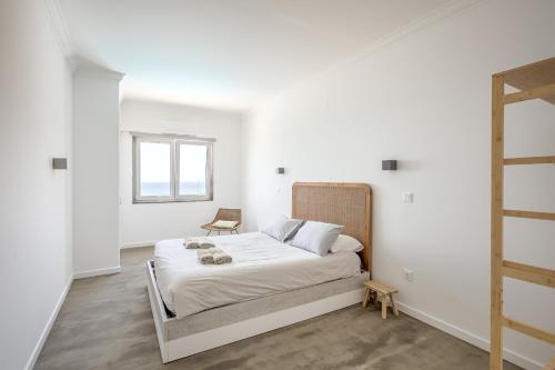 a white bedroom with a bed and a window at Ericeira Bay in Ericeira