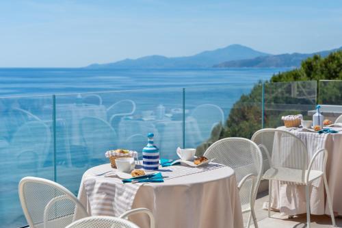a table with white tables and chairs with a view of the ocean at B&B Residence Eco Del Mare in Palinuro